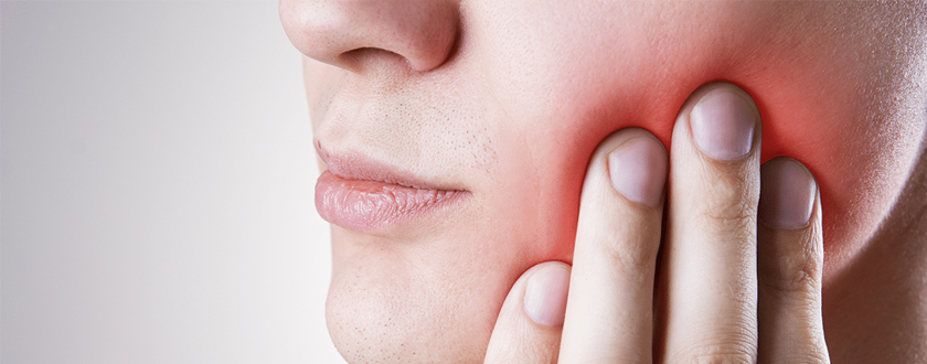 Woman holding her cheek from tooth pain